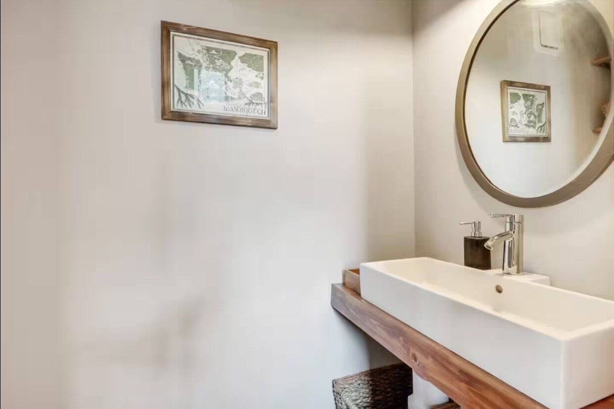 Powder room with floating wood vanity and round mirror