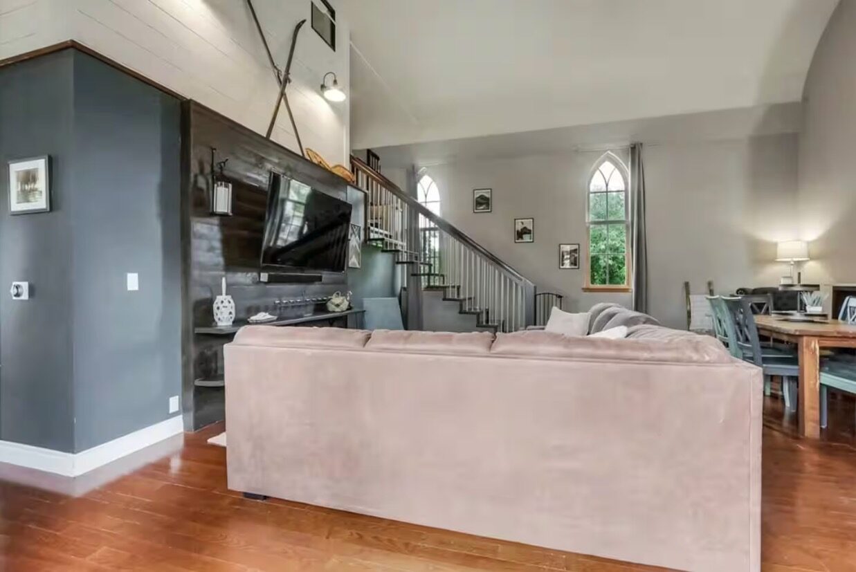 Living room with TV, shiplap accent wall, and staircase